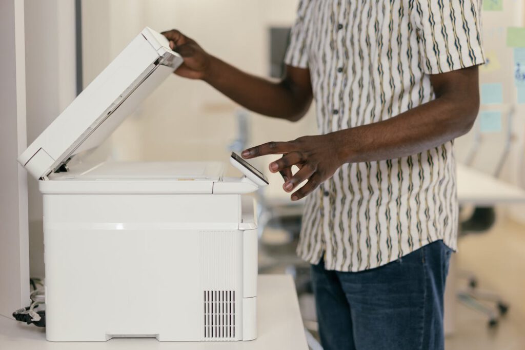 pexels-photo-9301887 Person operating photocopier in modern office setting, engaging with technology.